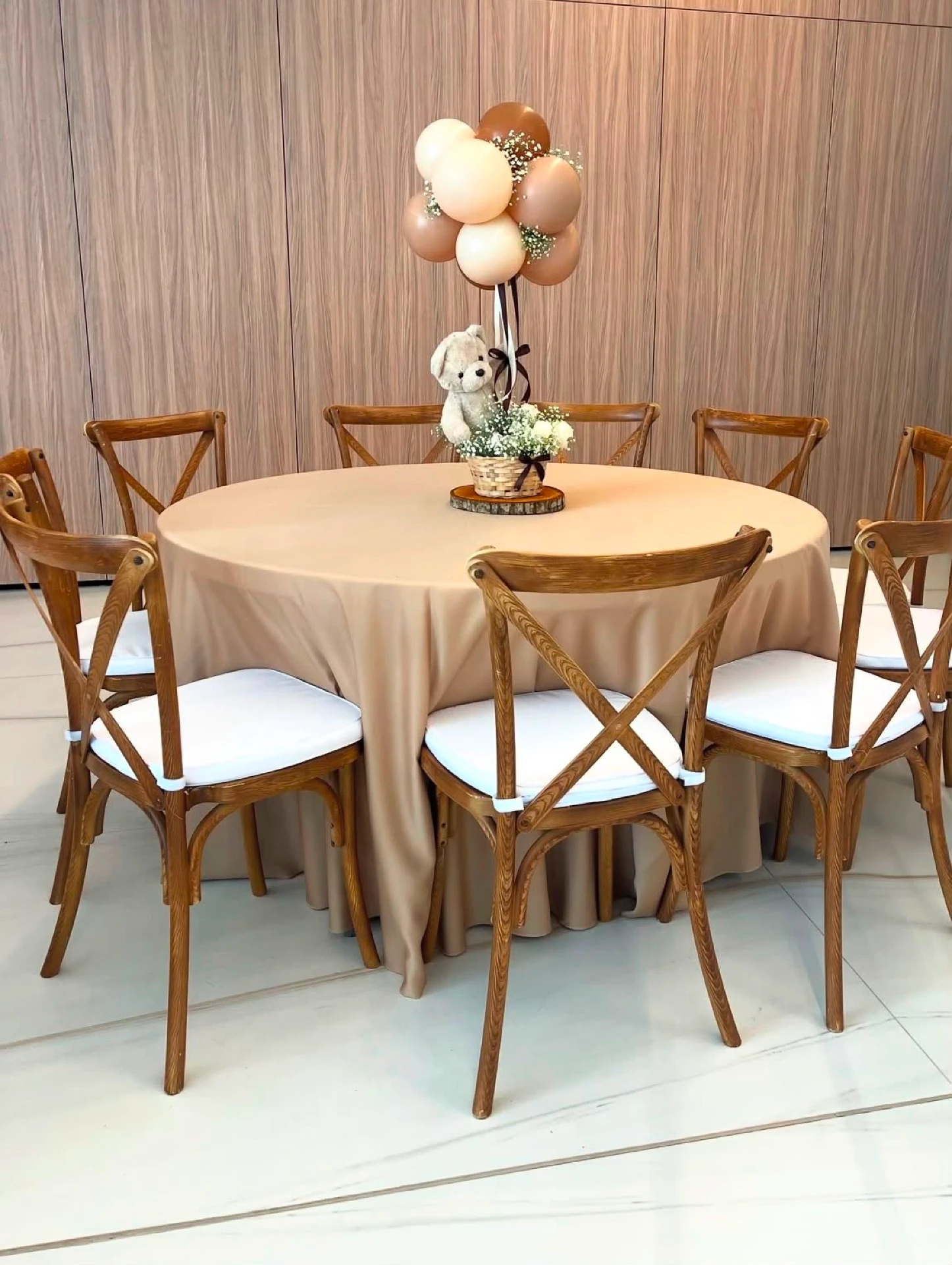 Round table with wooden crossback chairs and floral centerpiece