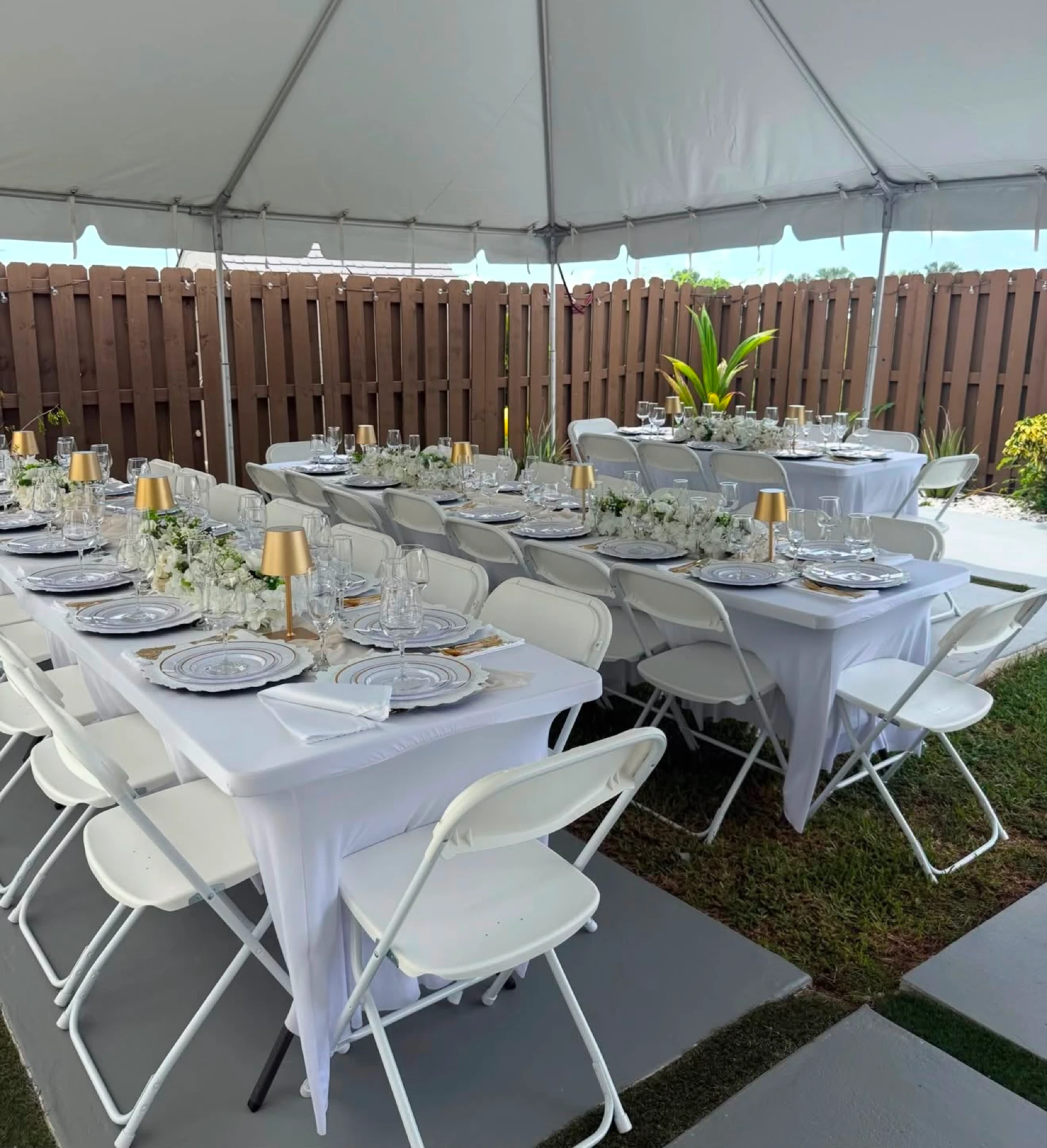 Outdoor tent reception with long banquet tables and white chairs